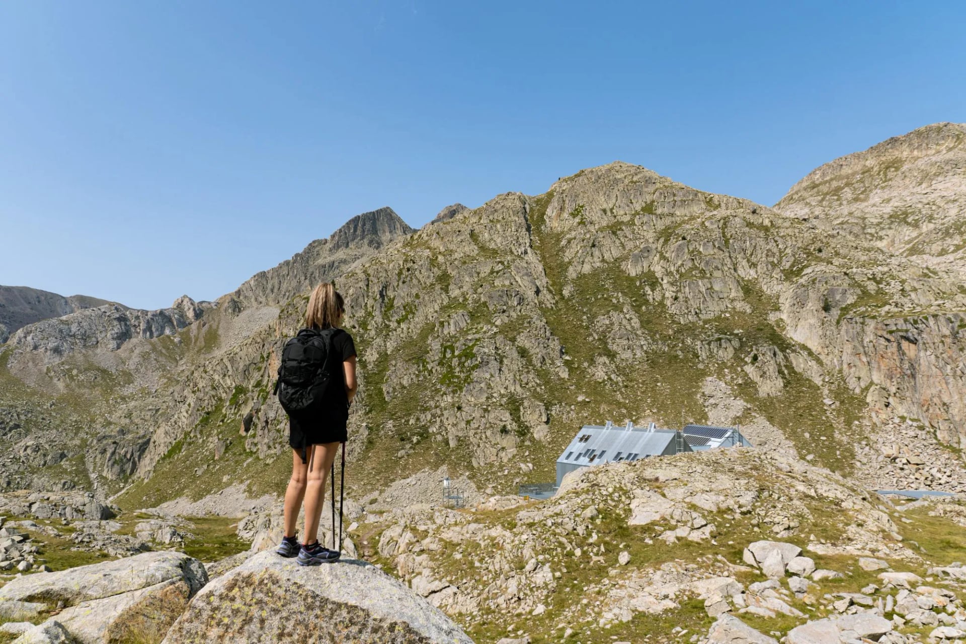 Walker standing on rock below the grey peaks around the Cap de Llauset refuge