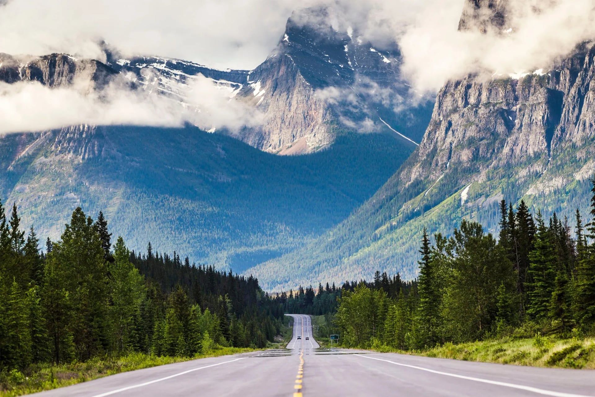 A straight road running towards a large range half wrapped in cloud