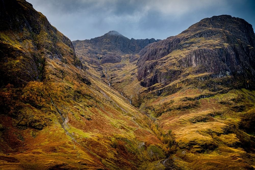 Gyldent efterårsgræs under stejle skråninger i Glen Coe