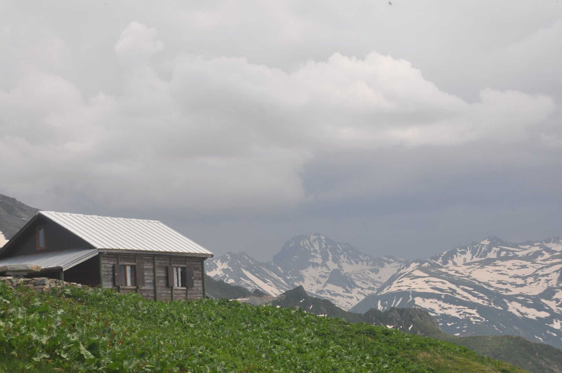 A timber mountain hut below snow streaked peaks