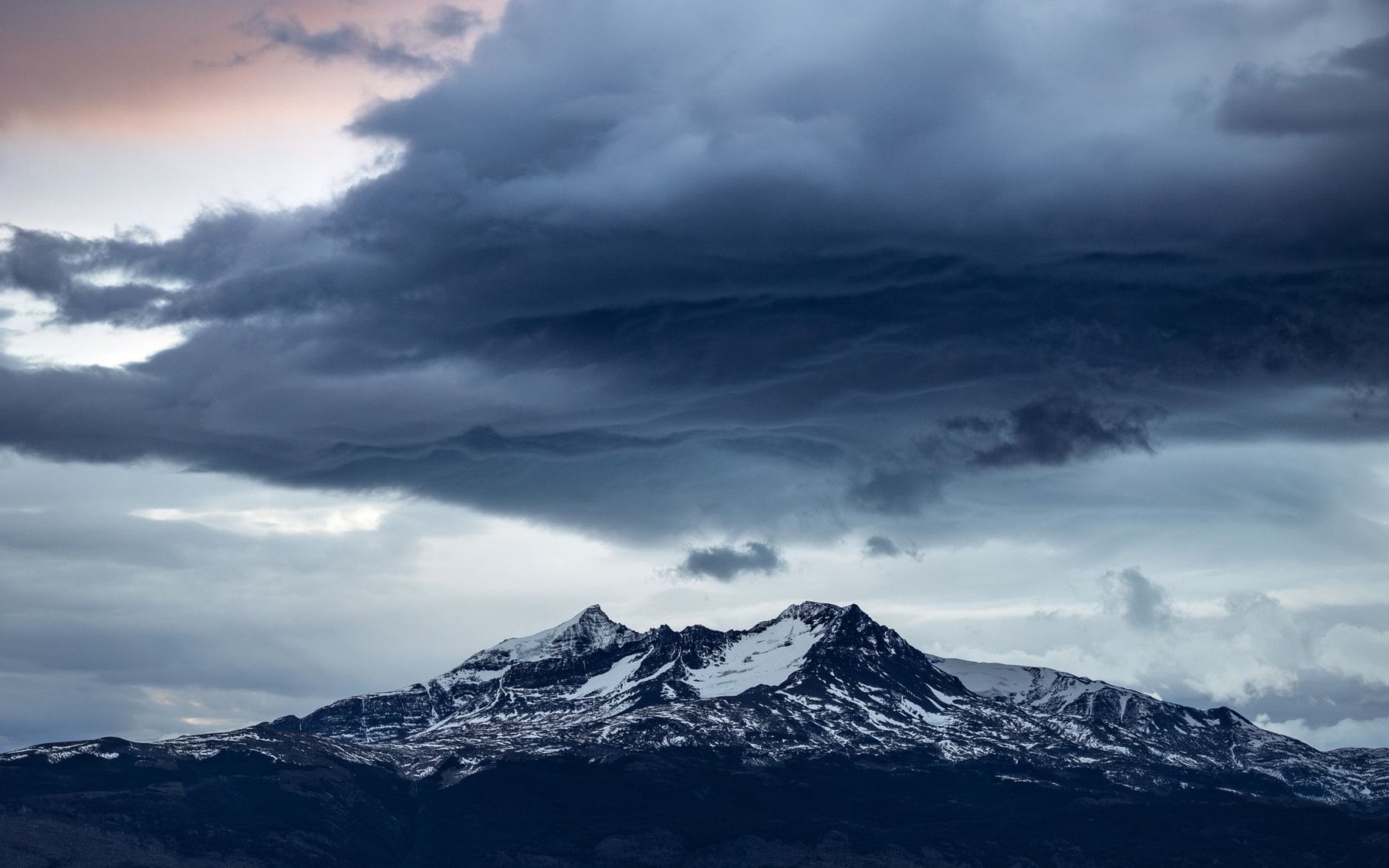 Storm cloud gathering over a snow covered range