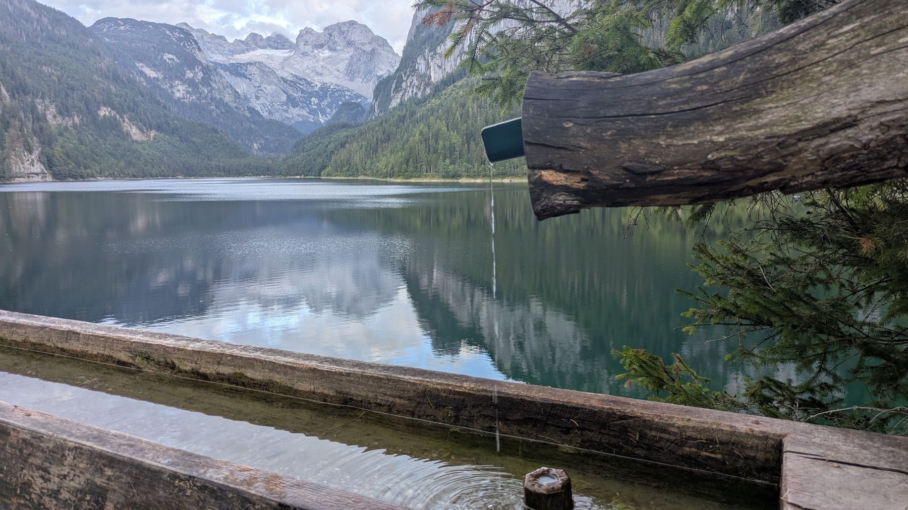 A wooden trough of spring water beside an alpine lake
