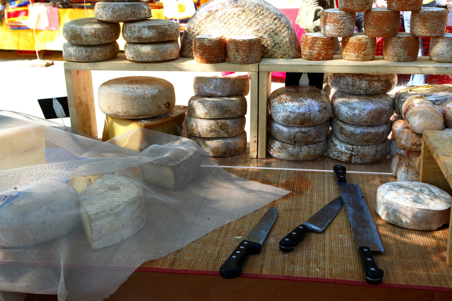 Aged cheese rounds and cutting knives on a stall selling what the region actually makes