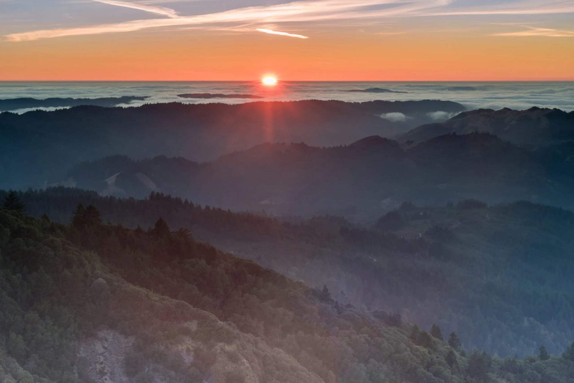 Ridges running away below Mount Tamalpais with the sun low over a sea of cloud
