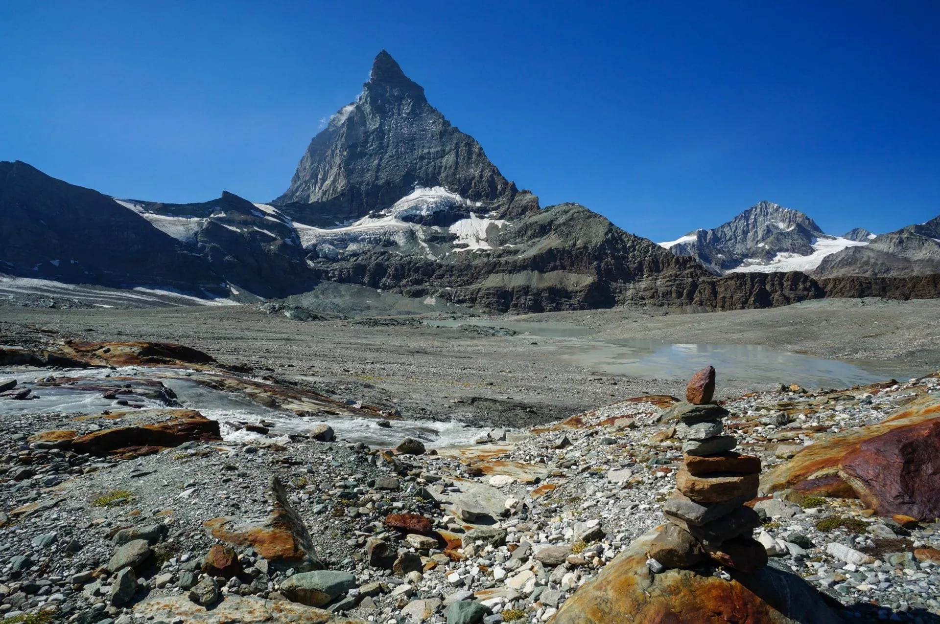 De Matterhorn voorbij een stenen gletsjervlakte met een wandelaar cairn op de voorgrond