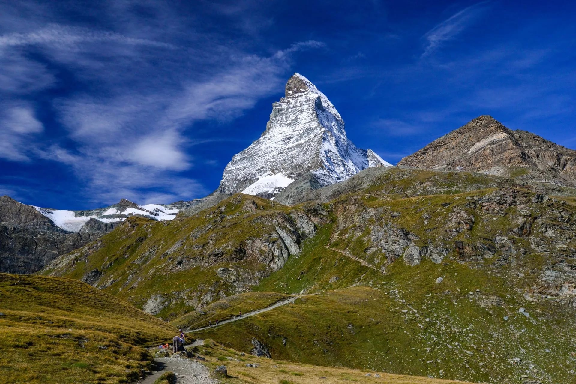 De Matterhorn in zijn piramideprofiel boven groene hellingen op het pad van Schwarzsee