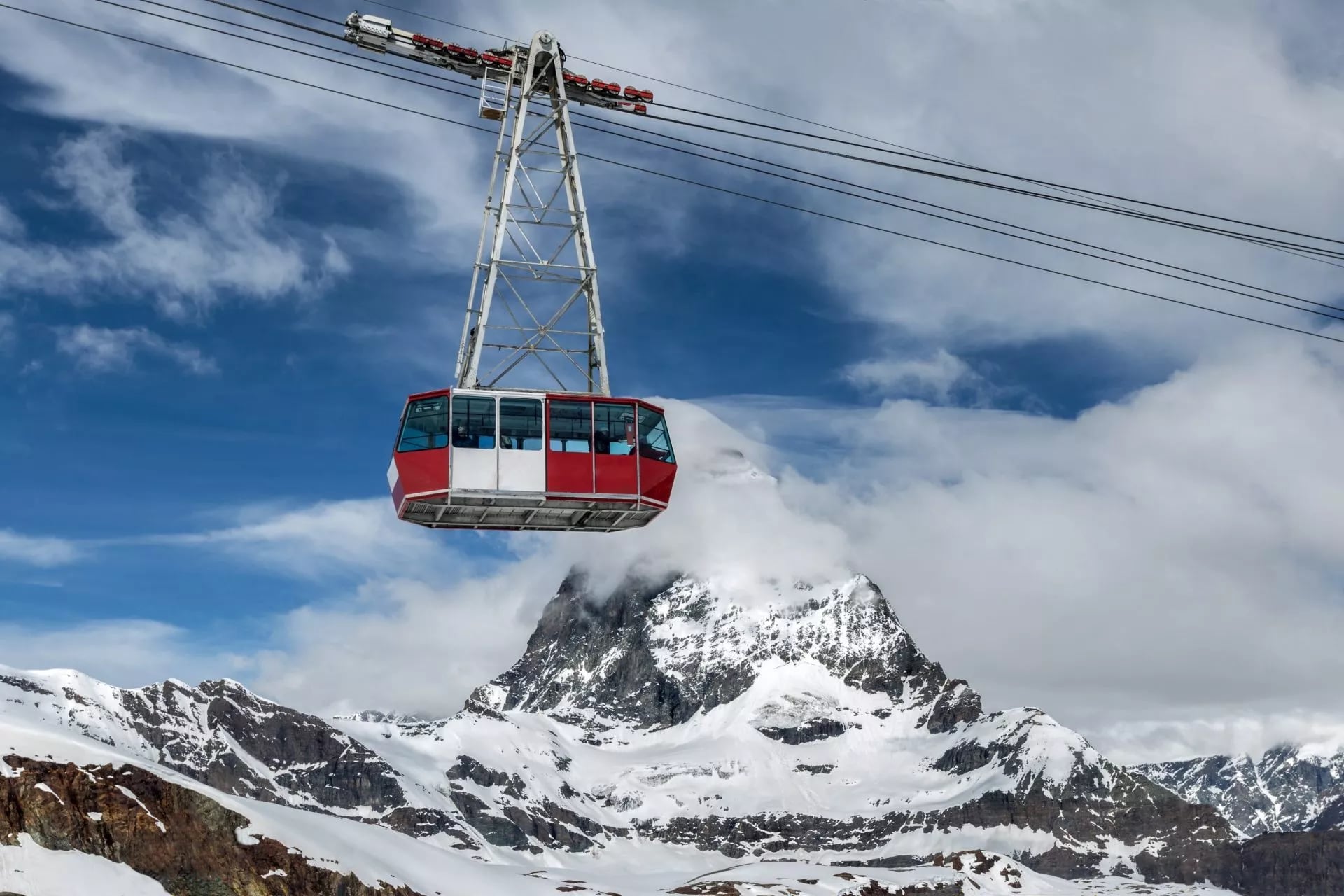 Een rode kabelbaan cabine aan zijn draad met de Matterhorn erachter
