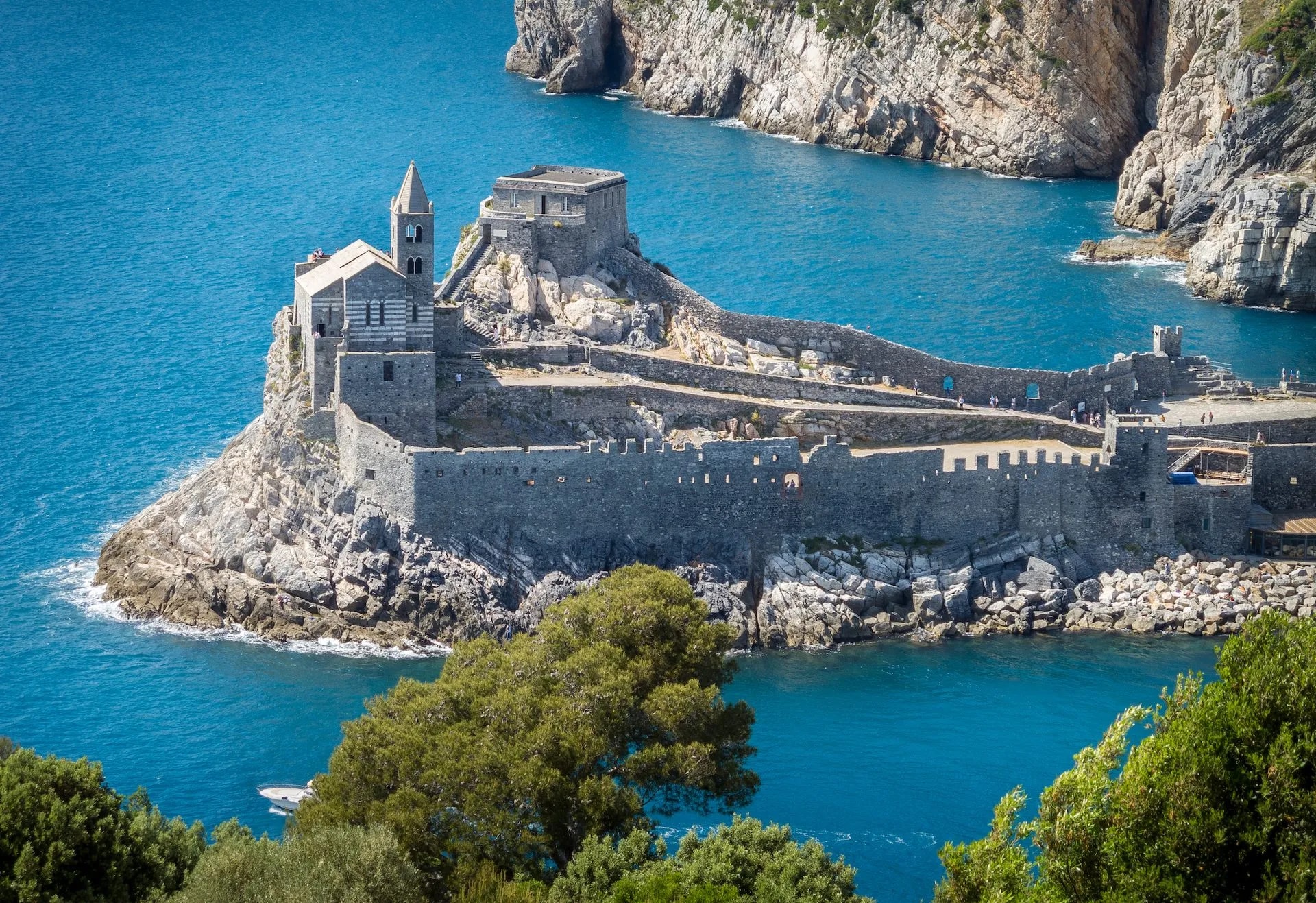 Church of St. Peter in Portovenere on rocky outcrop above bright blue Mediterranean sea.