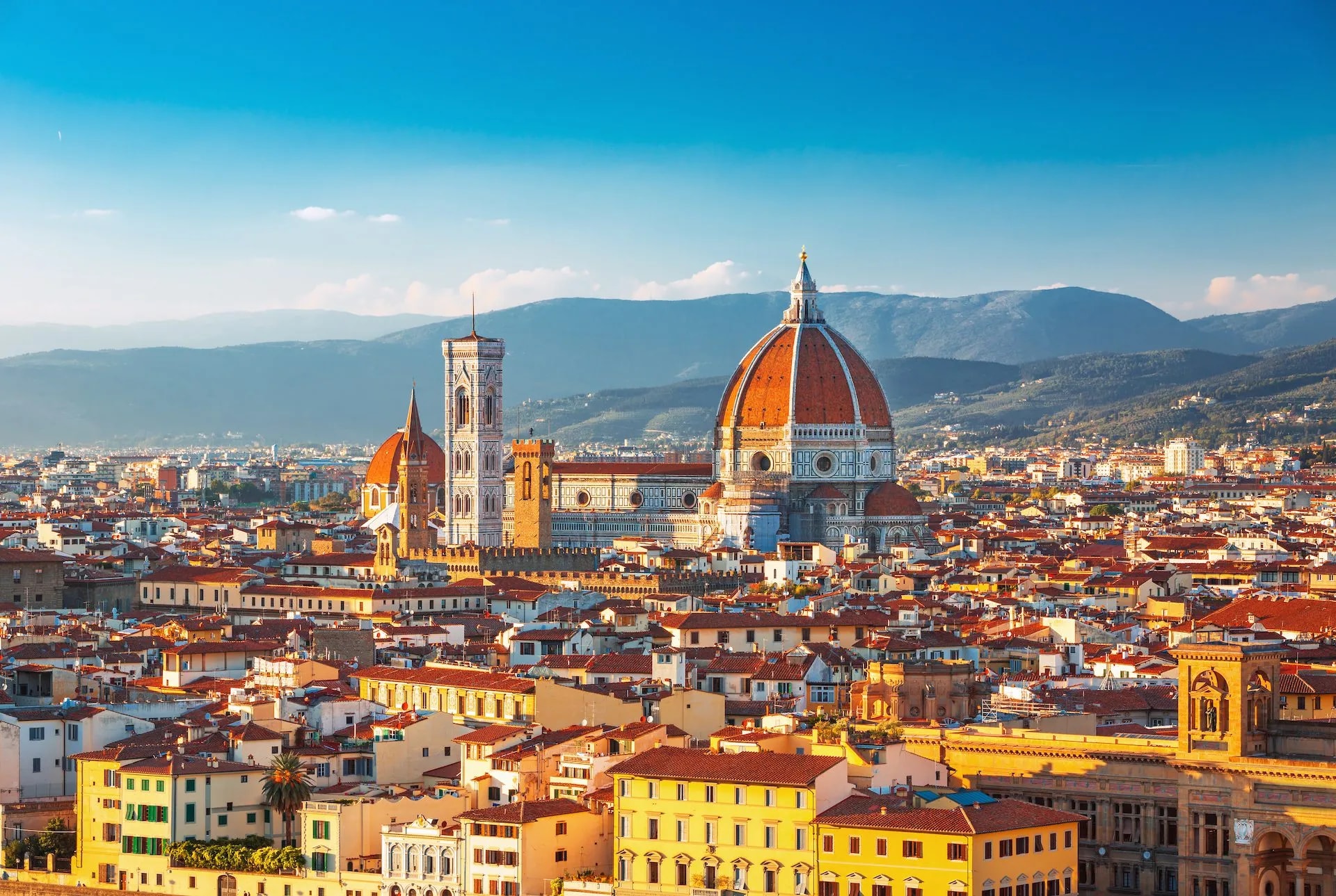 Florence cityscape with Duomo dome and Giotto's Campanile against blue sky and hills