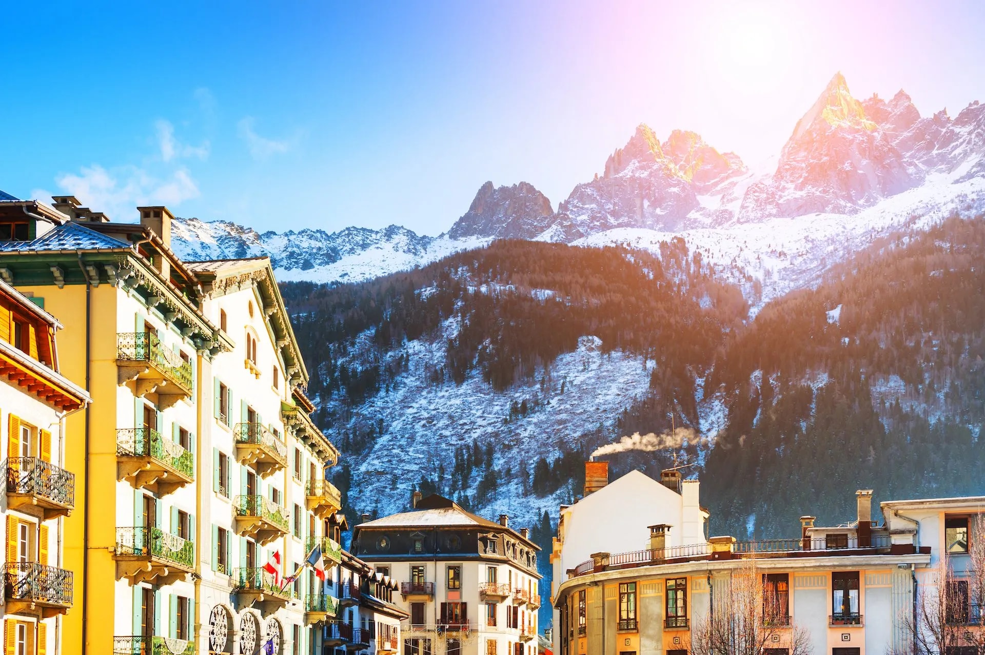 Chamonix-Mont-Blanc buildings below snow-capped alpine mountains under bright sun