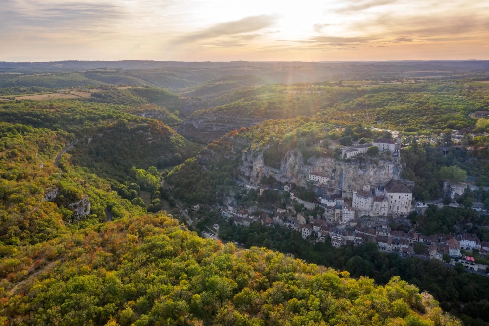 Cliffside village of Rocamadour nestled in a forested valley at sunset