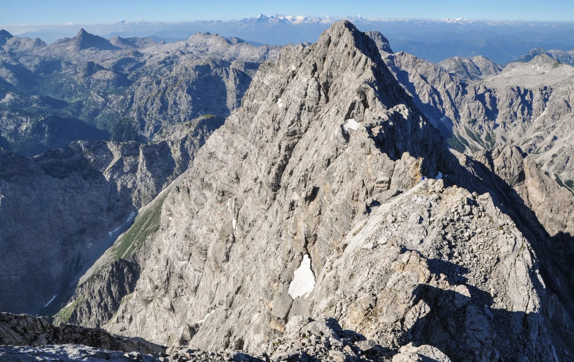 Rocky Watzmann mountain peak with hikers on the ridge under a clear blue sky
