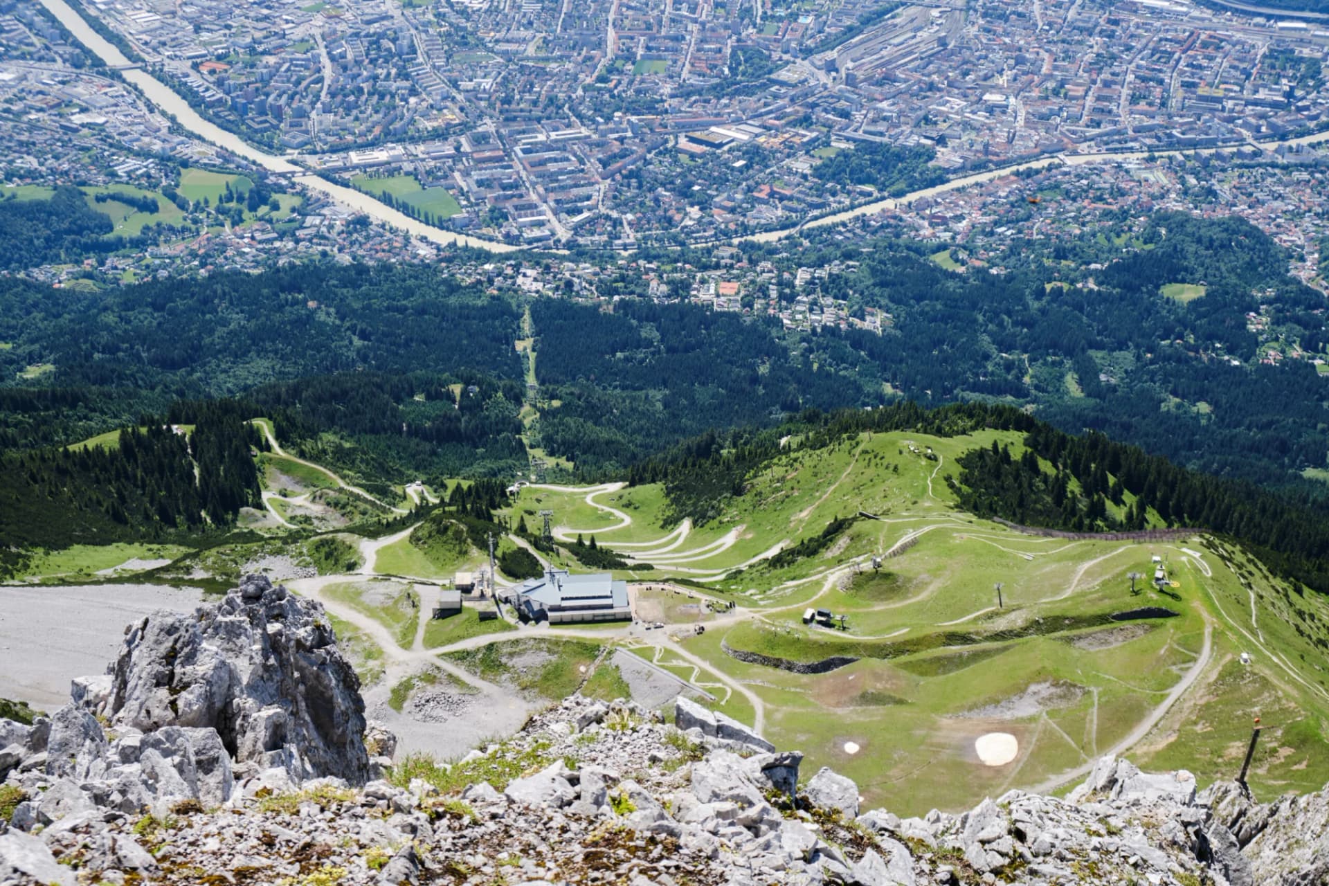 Innsbruck city from above Seegrube station of Nordkette cable car, with winding bike and hike trails. Top view.
