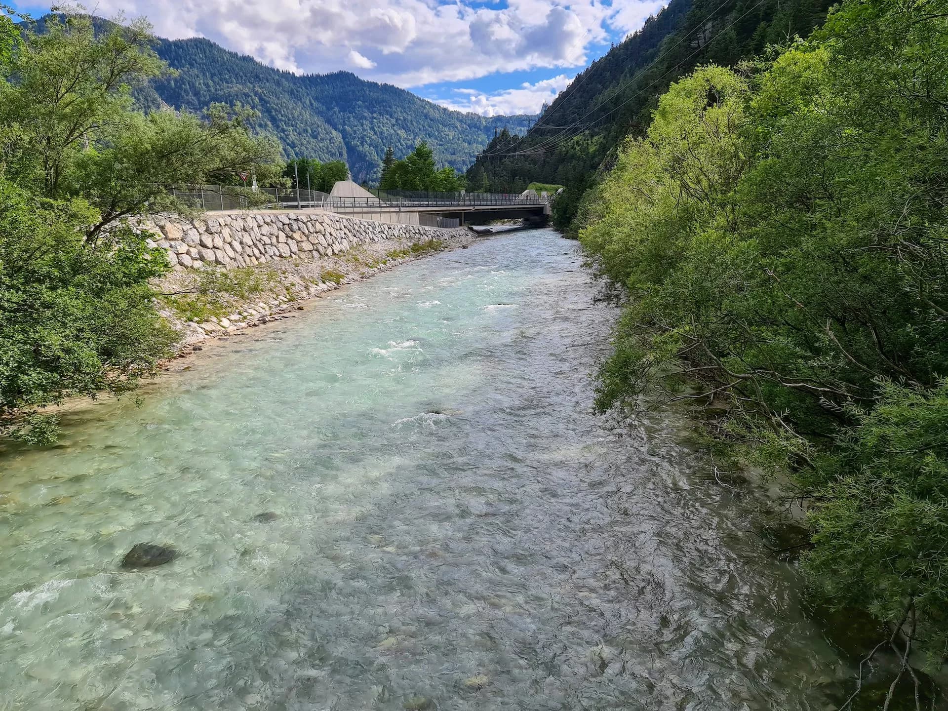 Clear river flowing through a valley with lush green mountains near Scharnitz.