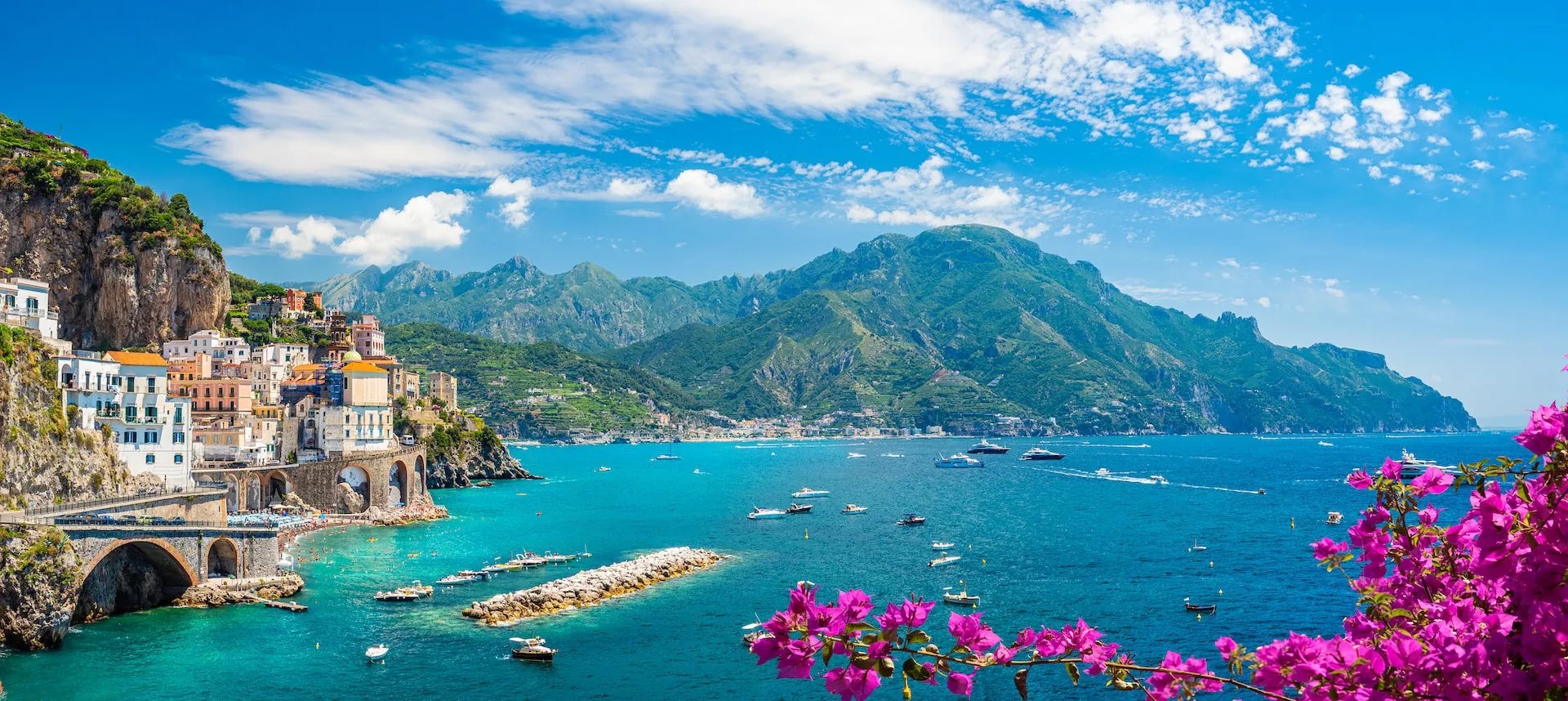 Coastal town of Atrani on the Amalfi Coast with colorful buildings, blue sea, and mountains.