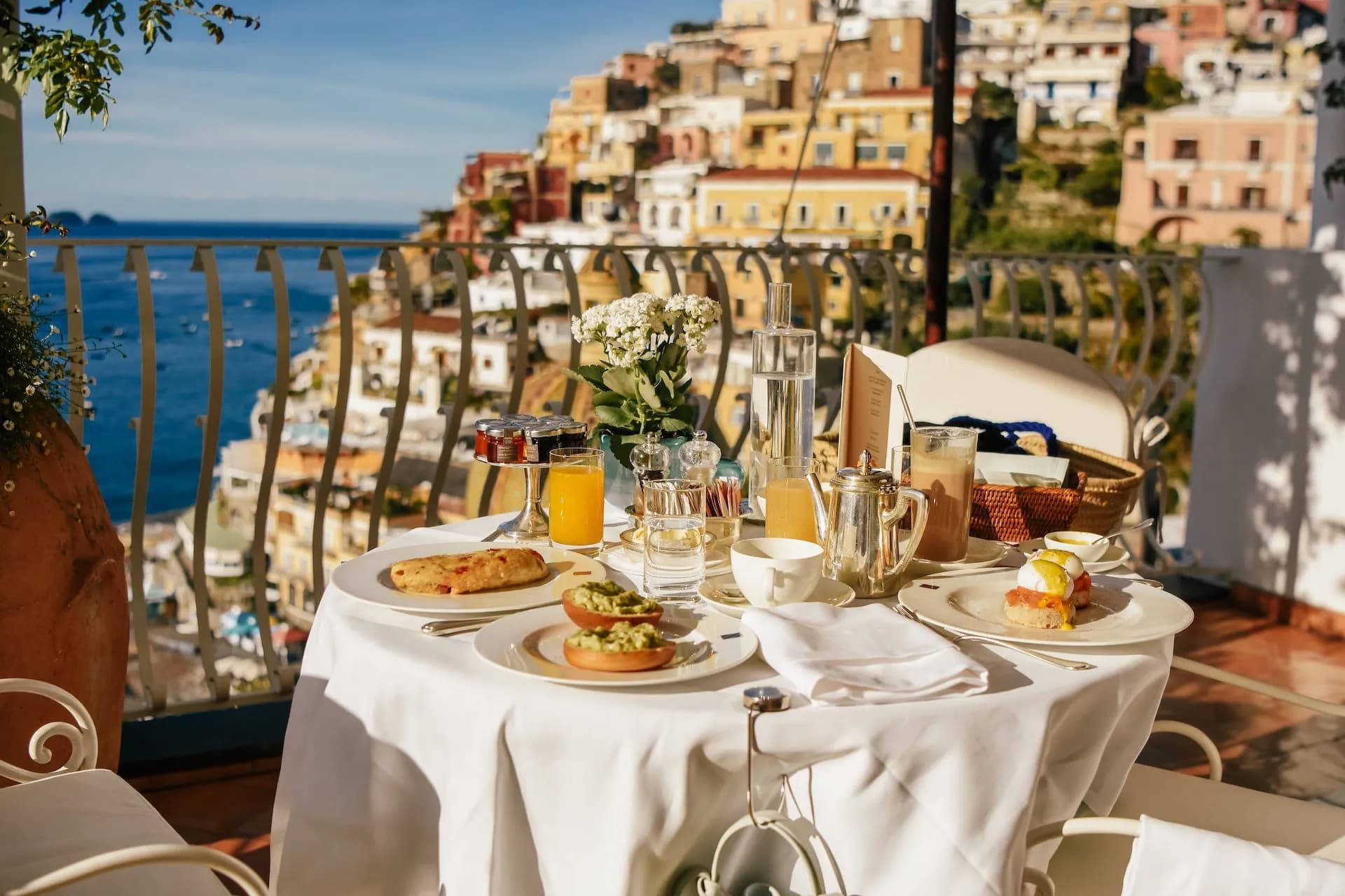 Breakfast on a terrace overlooking colorful cliffside buildings and the Mediterranean Sea in Italy.
