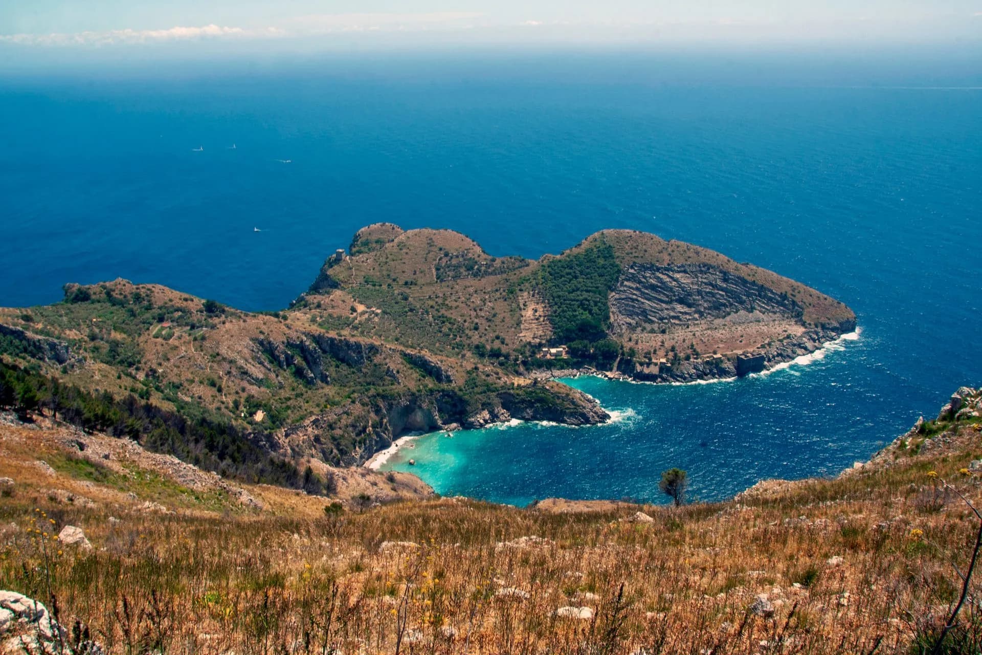 Landscape of Ieranto Bay in Sorrento from Punta Campanella with blue sea and arid hillside.