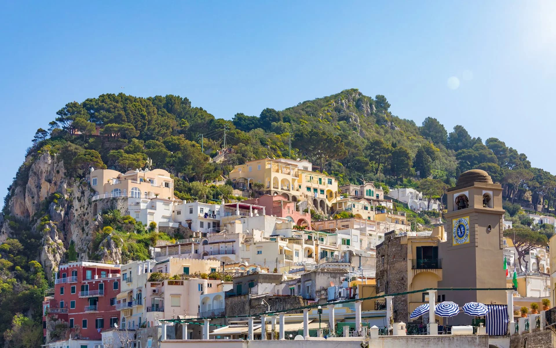 Daylight view of colorful buildings climbing a steep hill near the clock tower in La Piazzetta, Capri Island.
