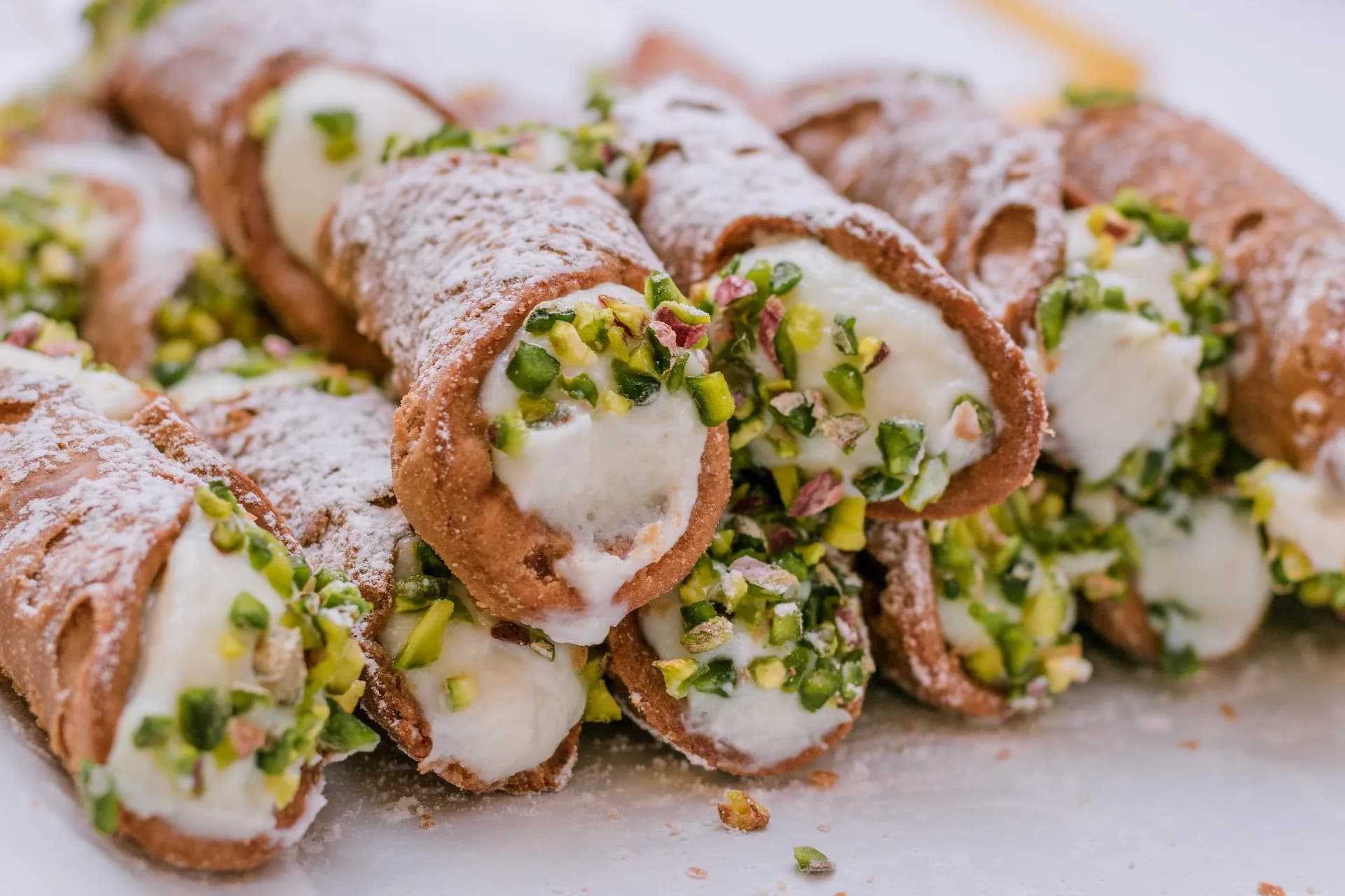 Cannoli pastries filled with cream, topped with pistachios and powdered sugar, Sicilian dessert