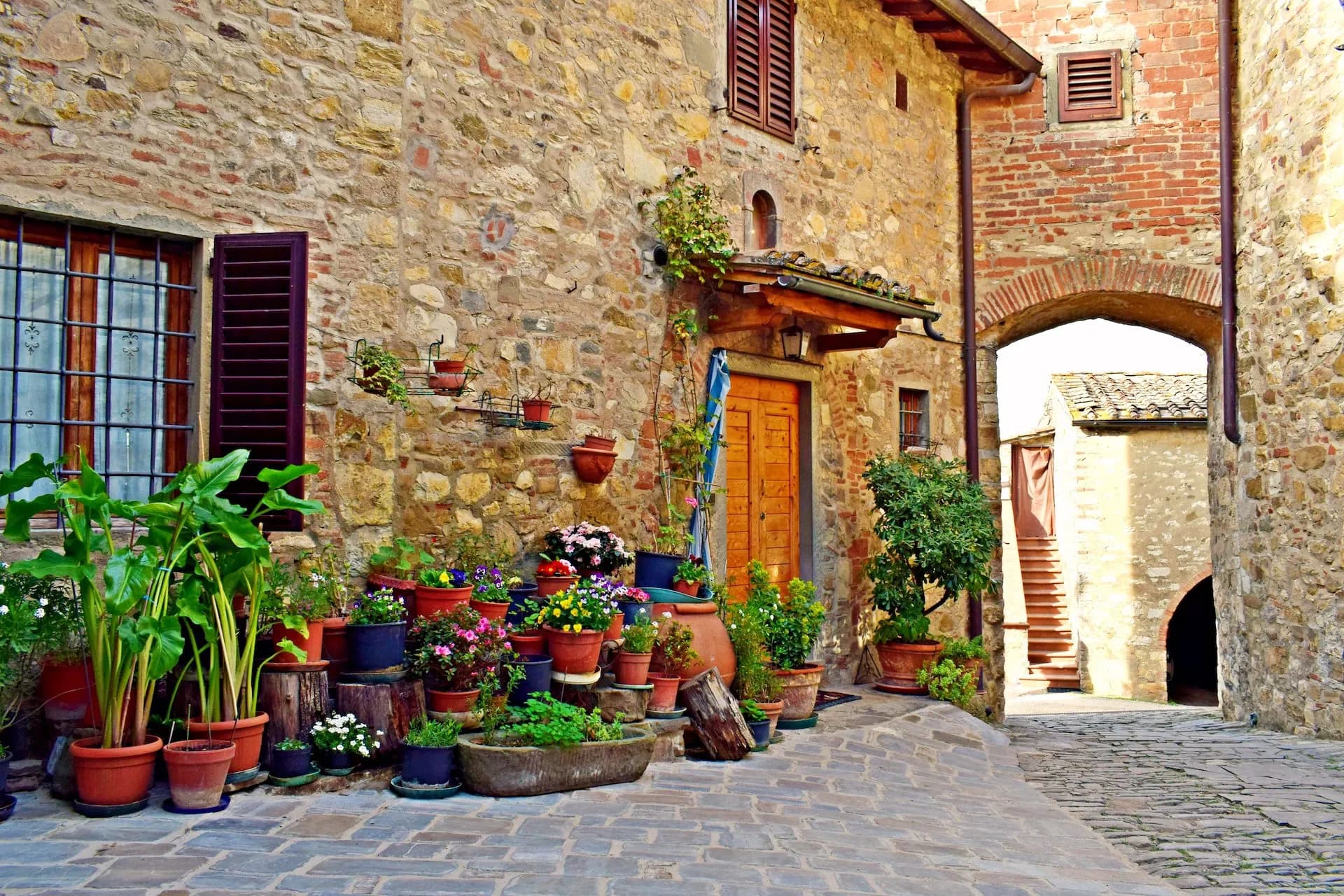 Stone alleyway entrance with potted plants decorating a rustic stone building in Montefioralle.