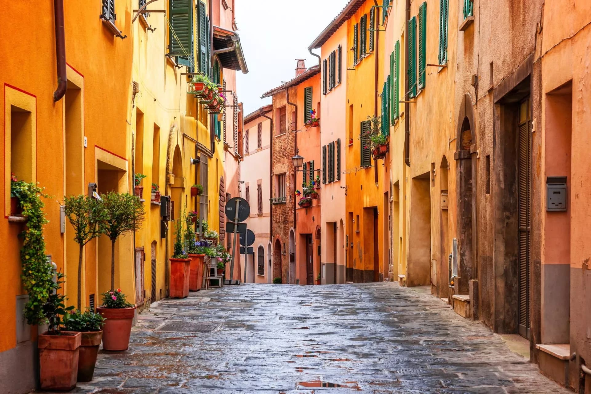 Cobblestone street in the old town of Montepulciano with colorful buildings and potted plants.