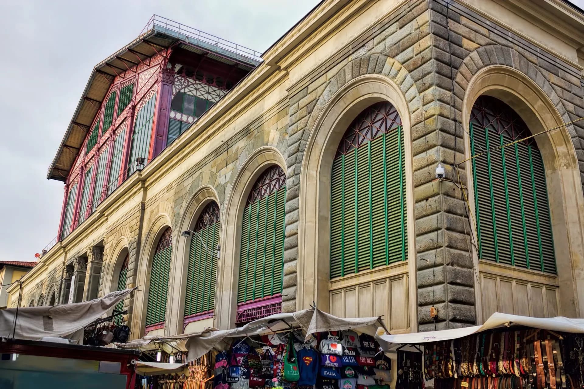 Mercato Centrale building exterior with arched windows and outdoor market stalls selling souvenirs.