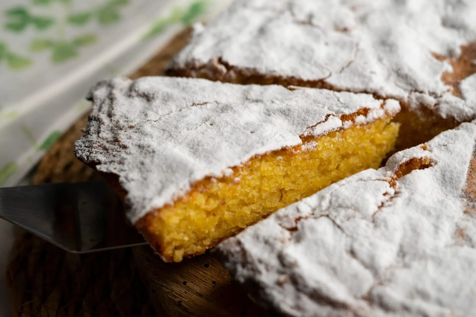 Tarta de Santiago almond cake slice being served, dusted heavily with powdered sugar