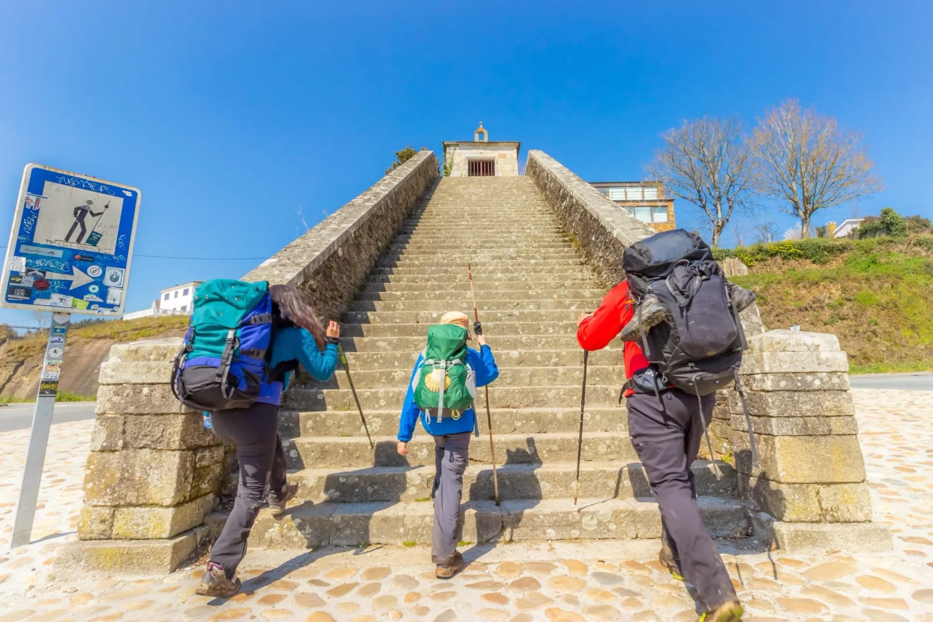 Two Adults and Child Pilgrims Ascending Stairs at City Entrance to Portomarin, along the Way of St James Pilgrimage Trail Camino de Santiago