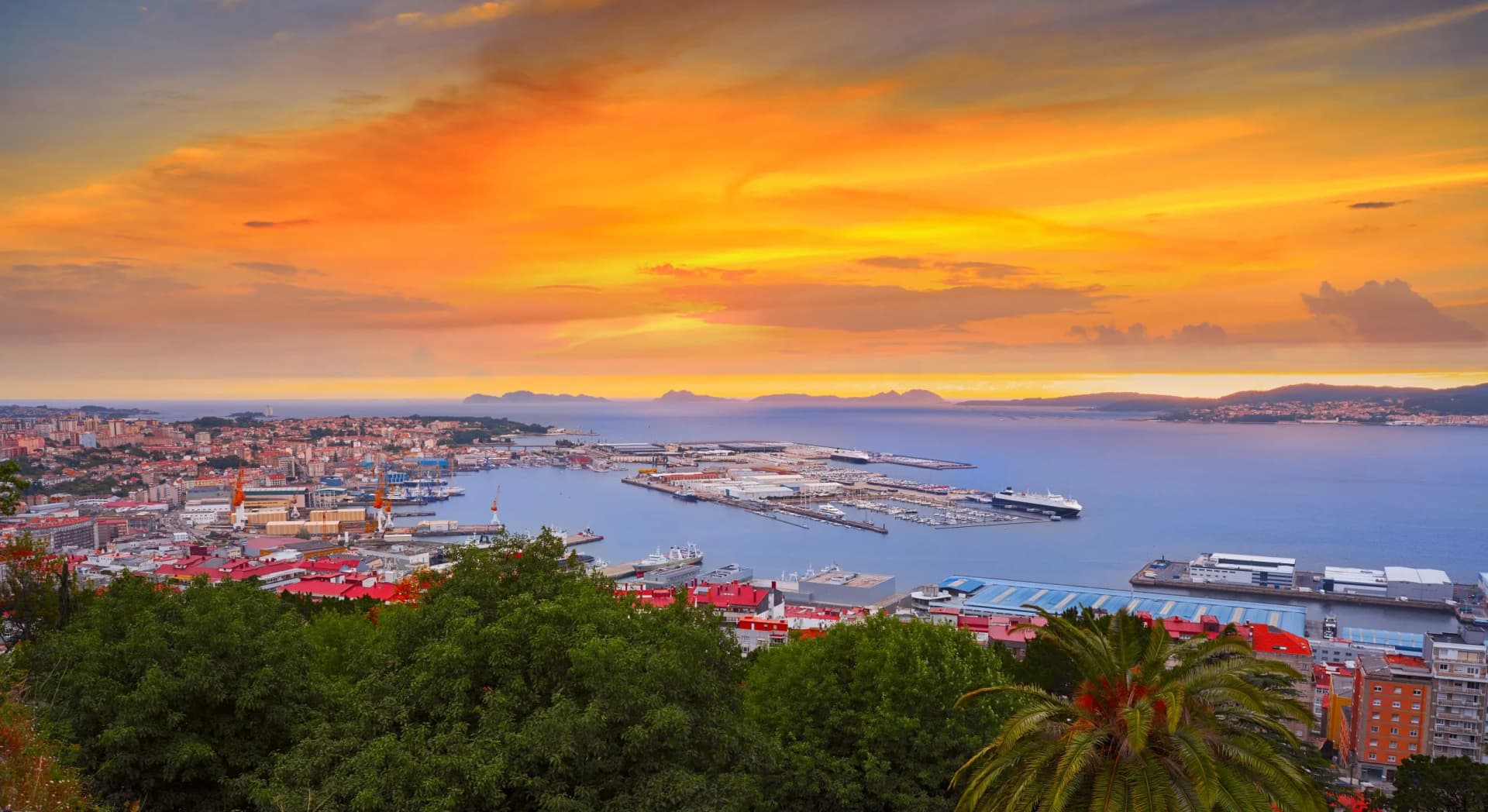 Vigo skyline and port with boats at sunset over the Atlantic Ocean.