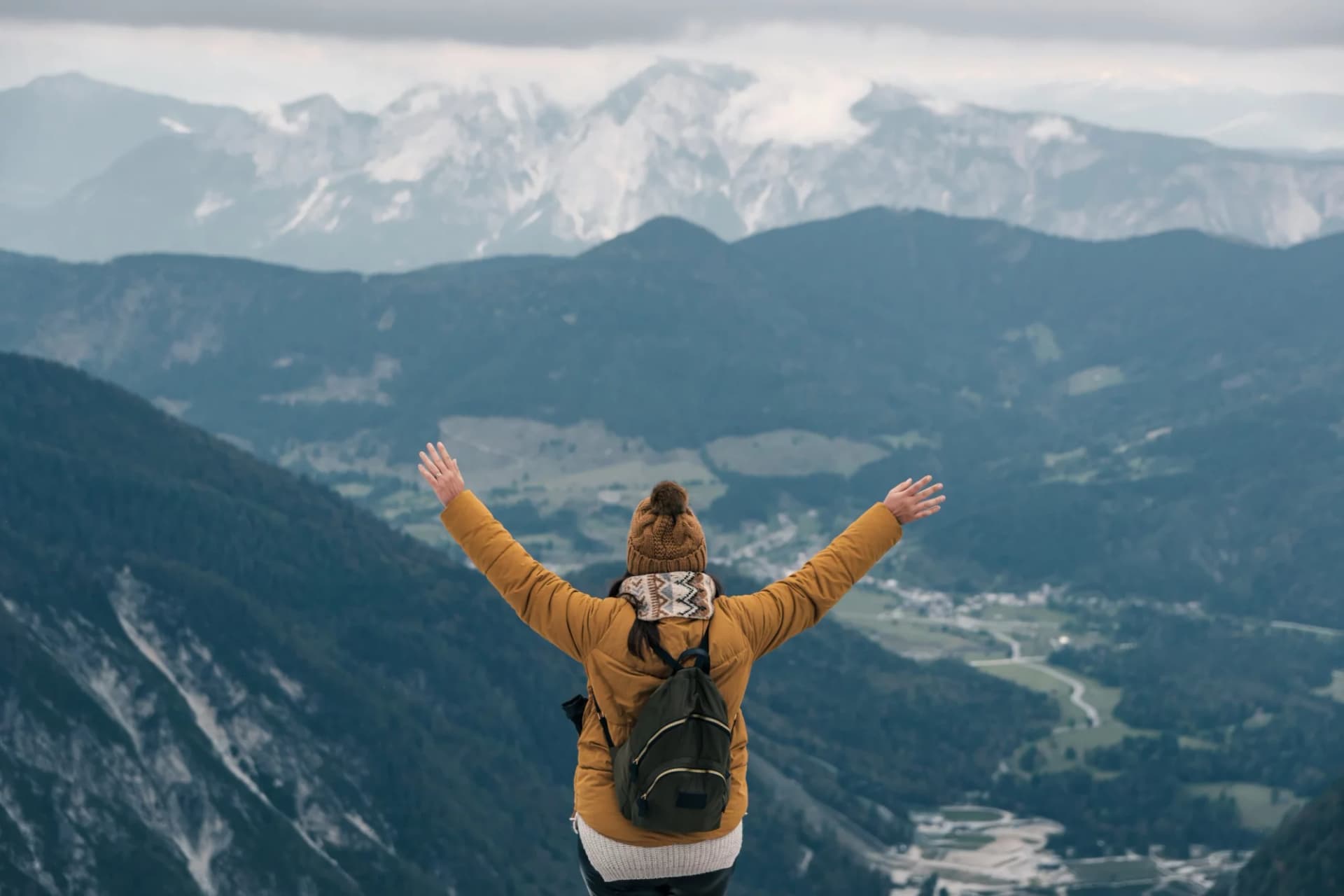 Hiker with outstretched arms overlooking Slemenova Spica in the Julian Alps.