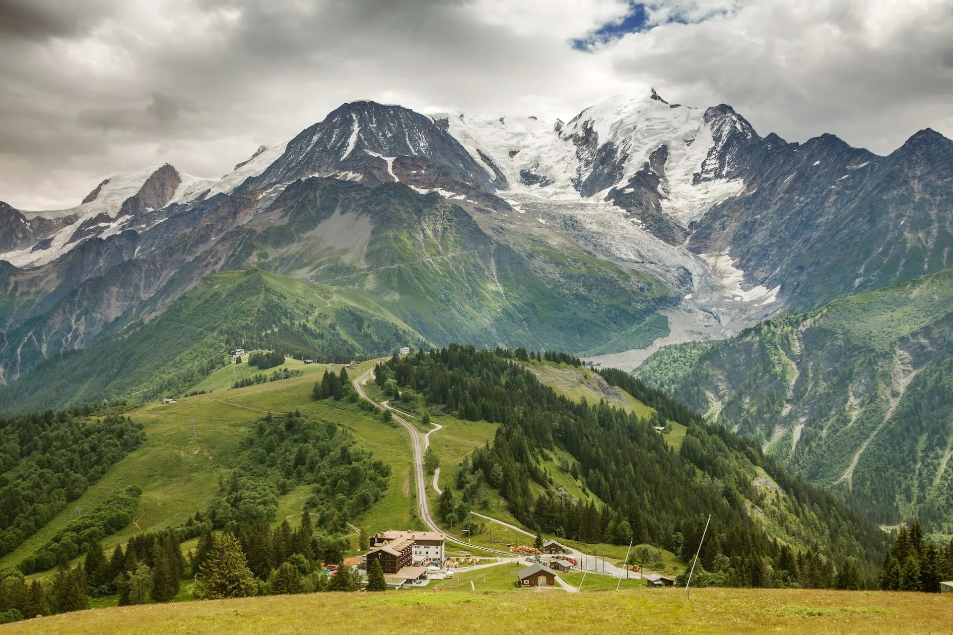 Mountain valley view in Les Houches with hotel, railway station, and snow-capped peaks.