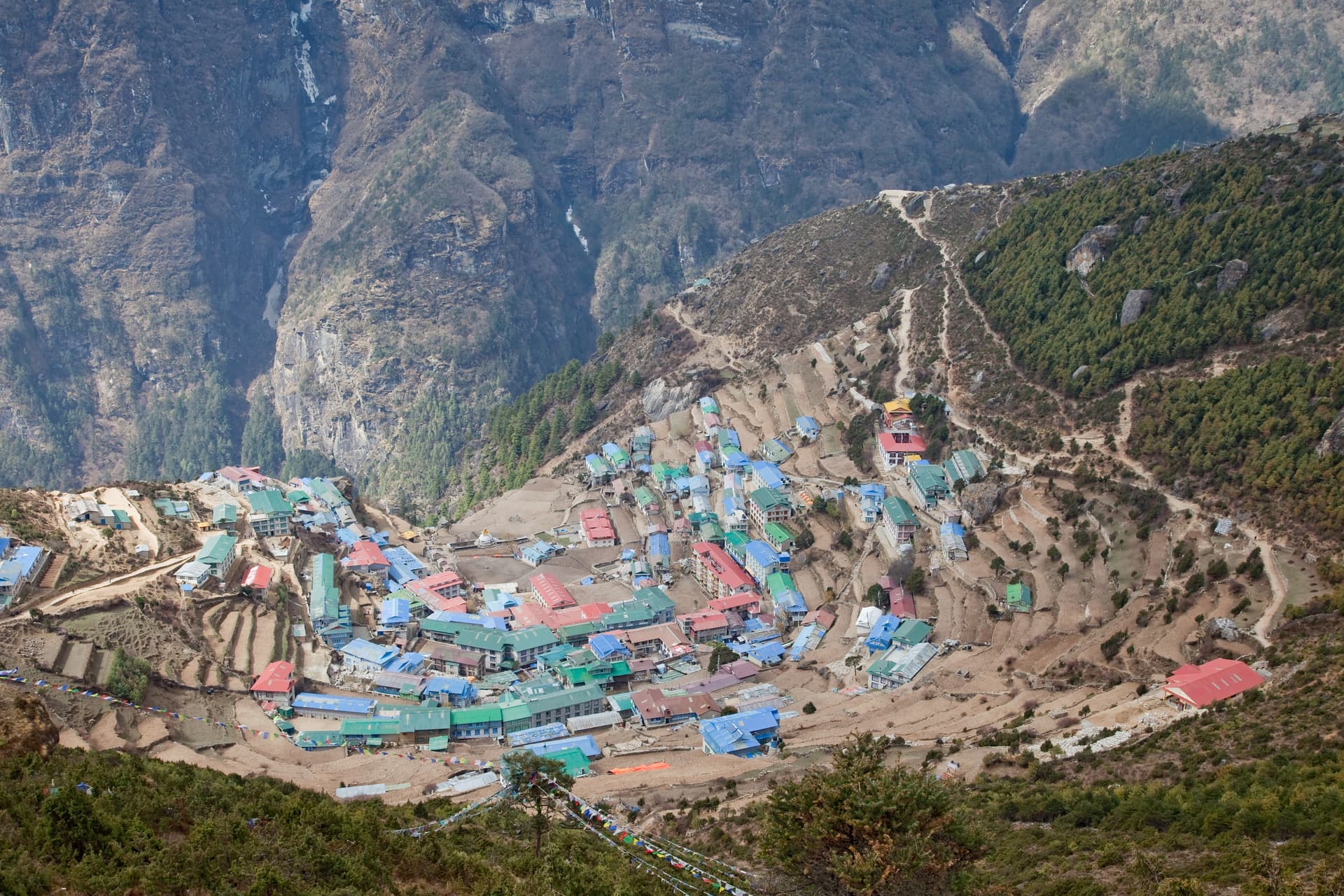 Village of Namche nestled on terraced hillside surrounded by steep Himalayan mountains.