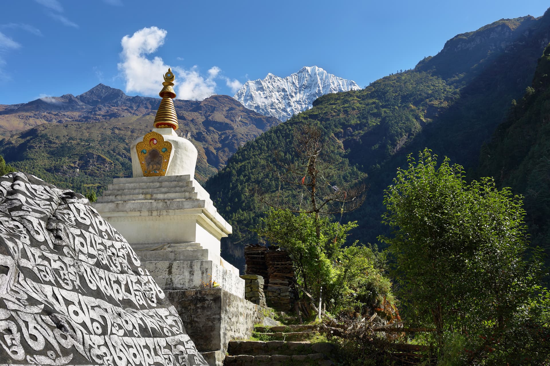 Buddhist stupa with inscribed stone and snow-capped Himalayas on the way to Namche.