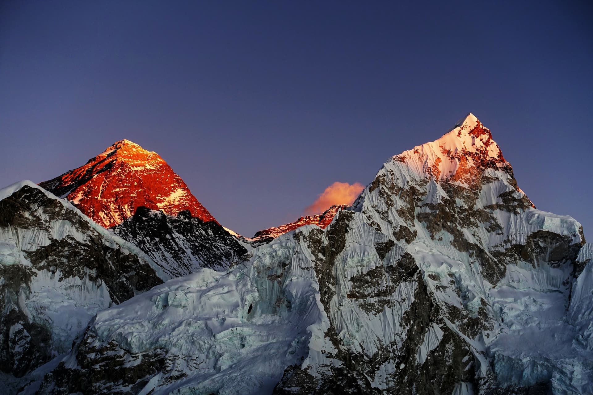 Sunset on Mt. Everest and Mt. Nuptse from Kala Patthar with snow and glaciers under a dark blue sky.
