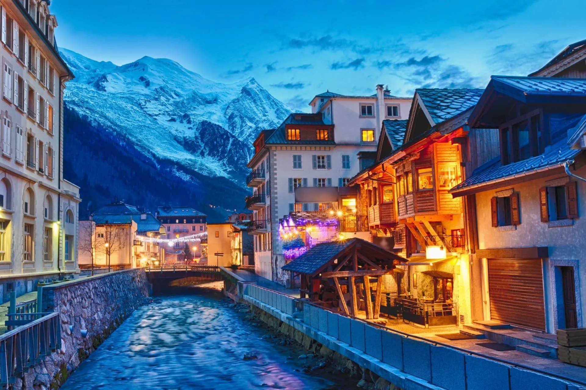 Nighttime view of Chamonix town with illuminated buildings and snow-capped mountains.