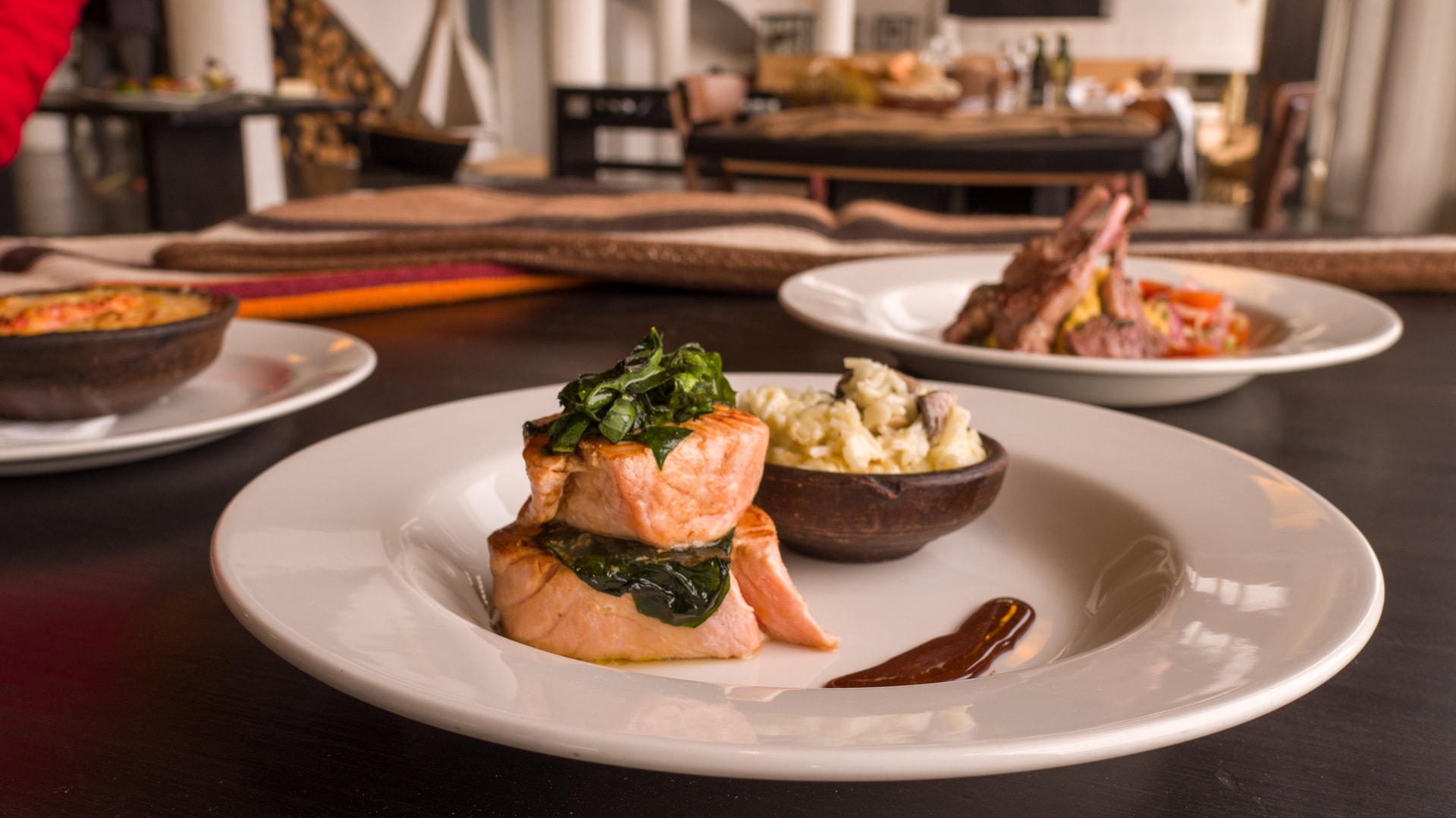 Salmon with greens and risotto in a bowl on a white plate at a restaurant in Southern Chile.
