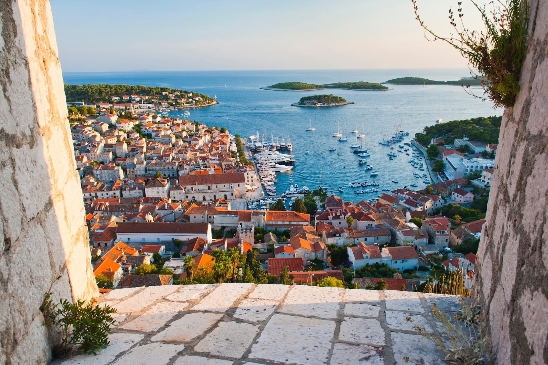 View of Hvar Island marina and town rooftops from a stone fortress overlooking the Adriatic Sea.