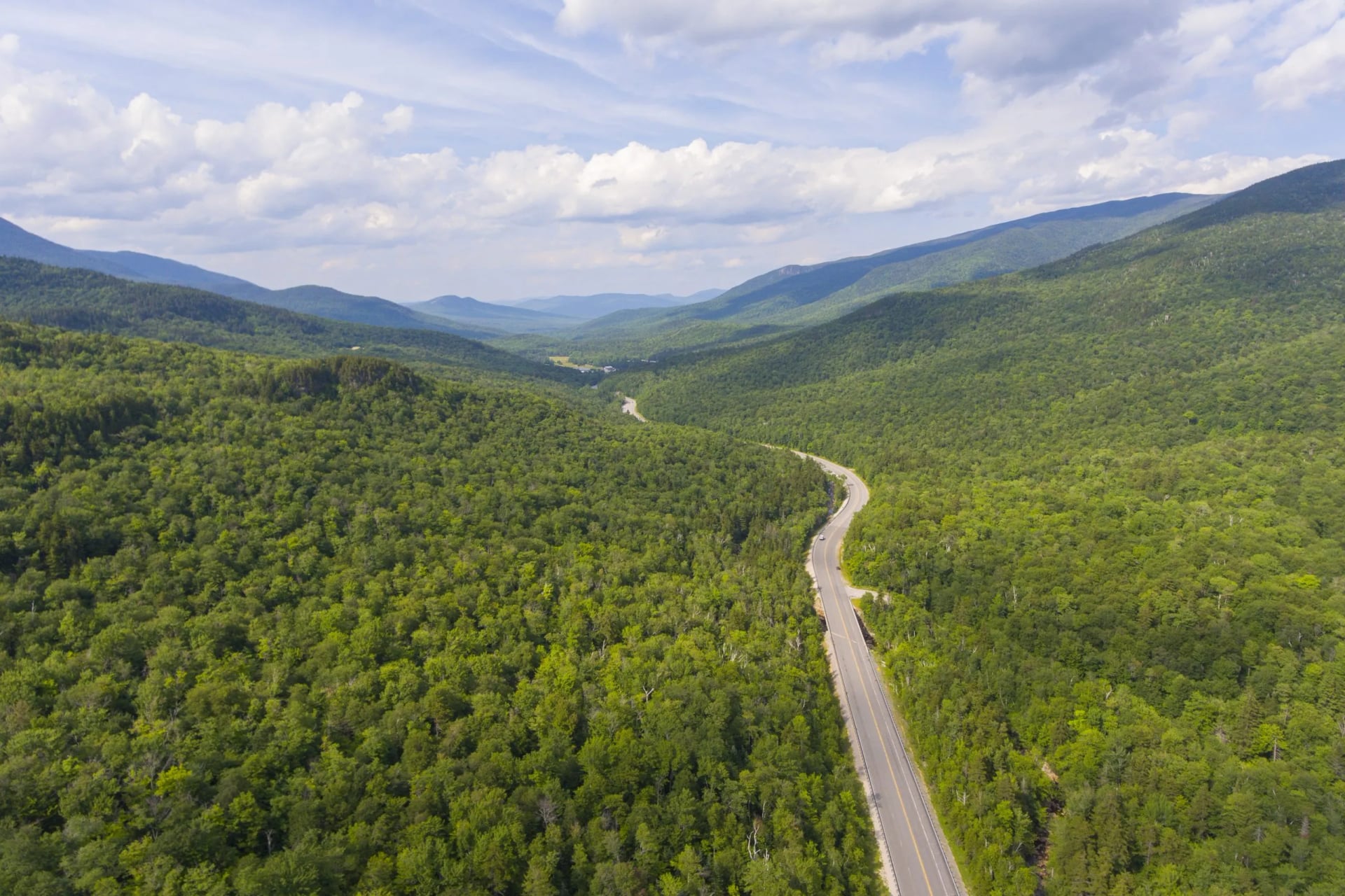A road winding through dense forested hills towards distant ridges
