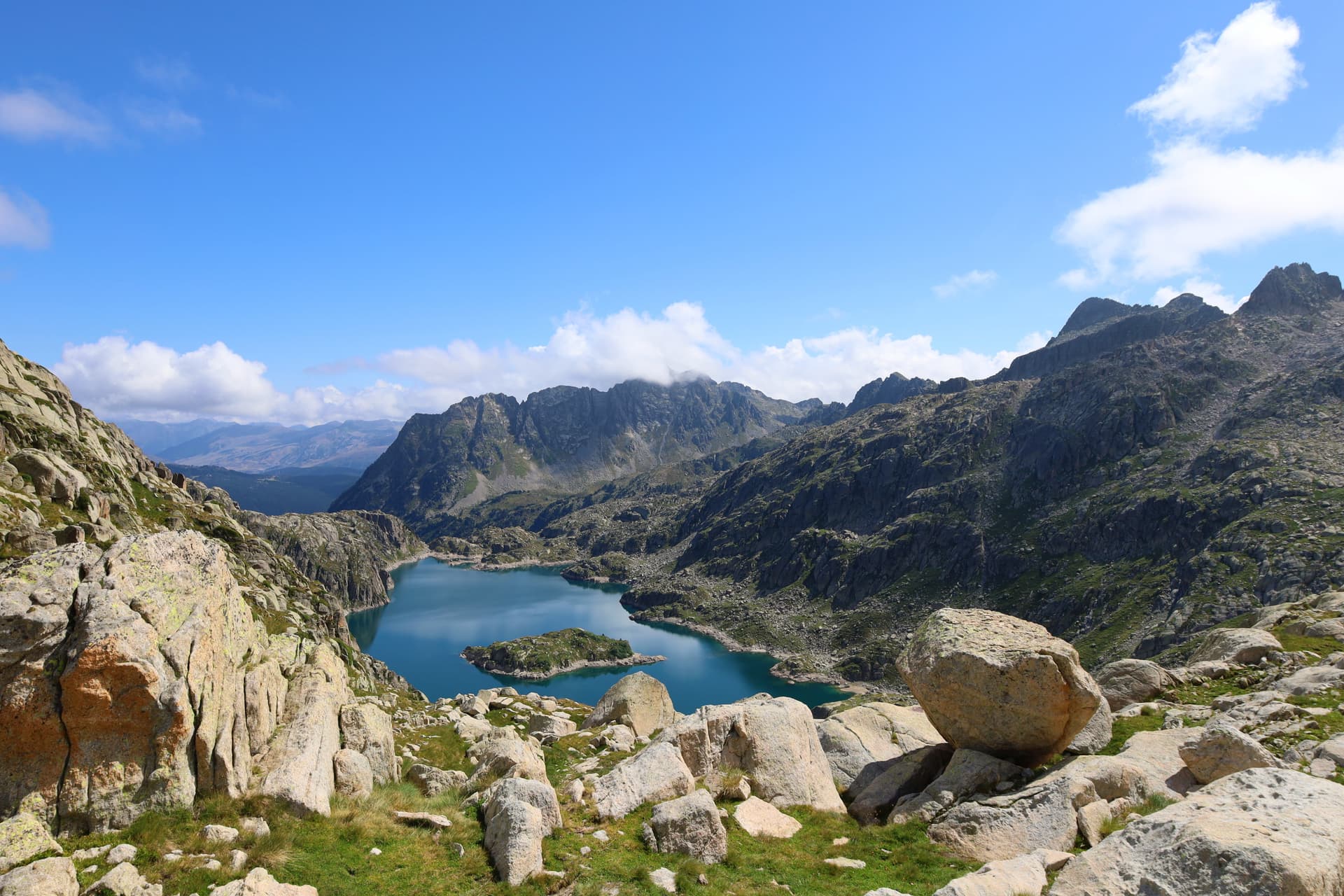 Alpine lake with turquoise water surrounded by rocky mountains under a blue sky in Maurici National Park.