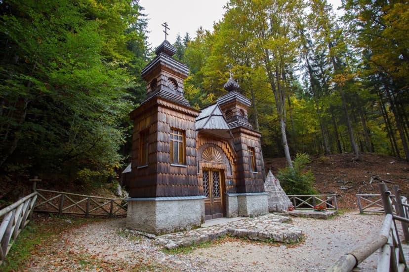 Russian chapel near Vršič Pass with wooden shingles surrounded by autumn forest.