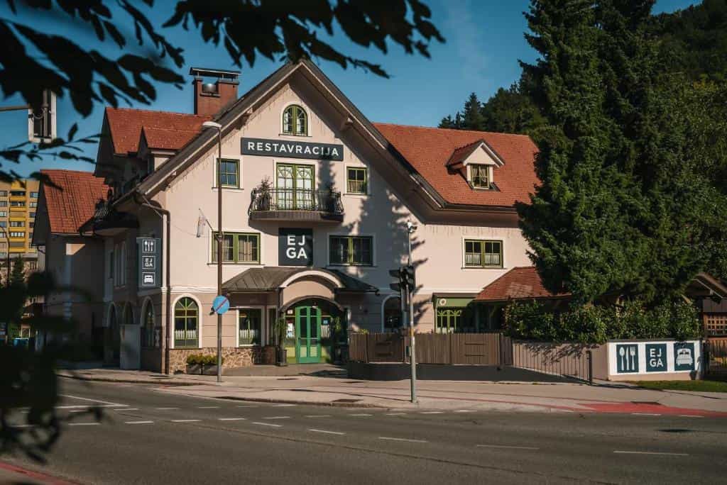 Guest house restaurant building with "RESTAURACIJA" sign near a wooded hillside