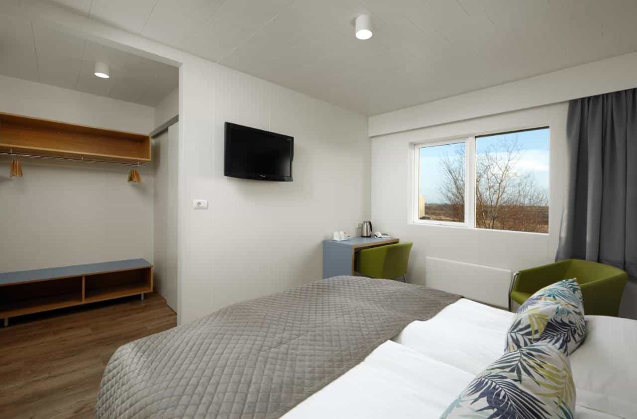 Hotel Klaustur room with twin beds, wall-mounted TV, and view of bare trees.