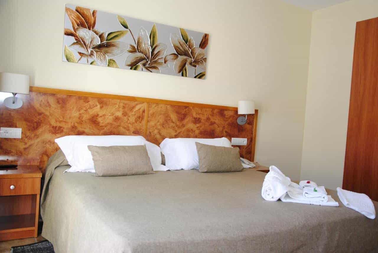 Hotel room with large bed, wood headboard, wall art, and folded white towels.