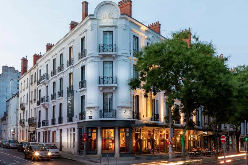 Hotel Saint Regis building facade at dusk on a city street with traffic and trees.