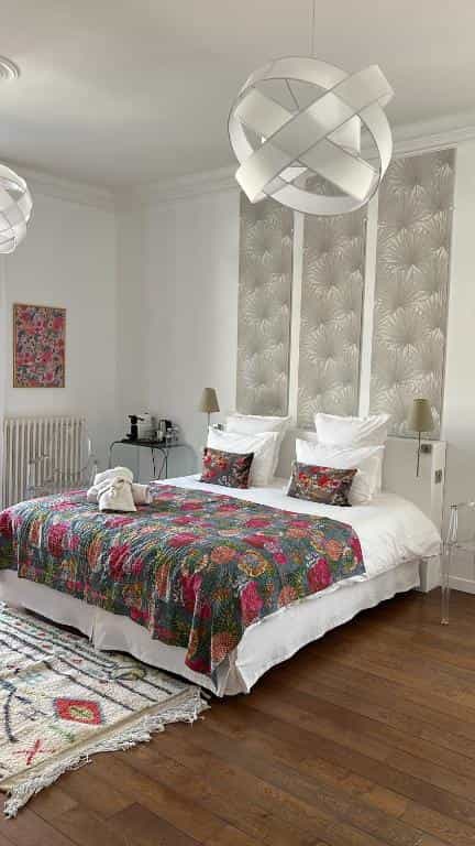 Bedroom in Maison Douce Arles with colorful quilt, modern lighting, and wood floor