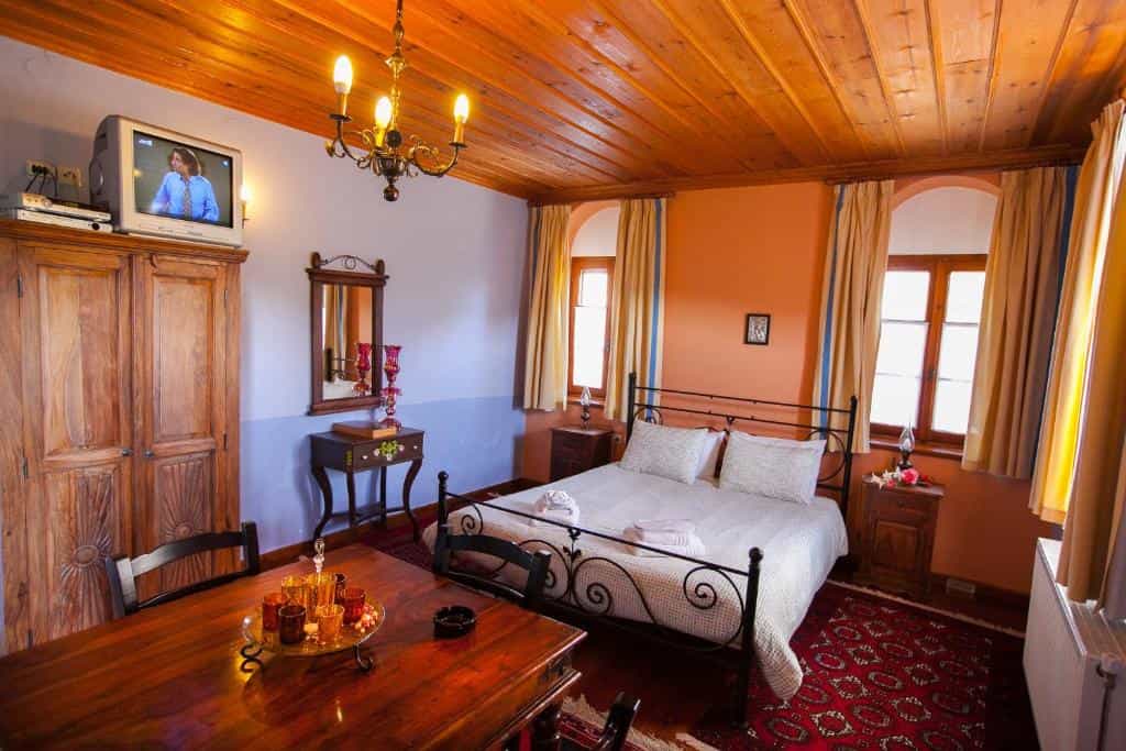 Hotel room with wooden ceiling, iron bed, and large wooden wardrobe in Machalas