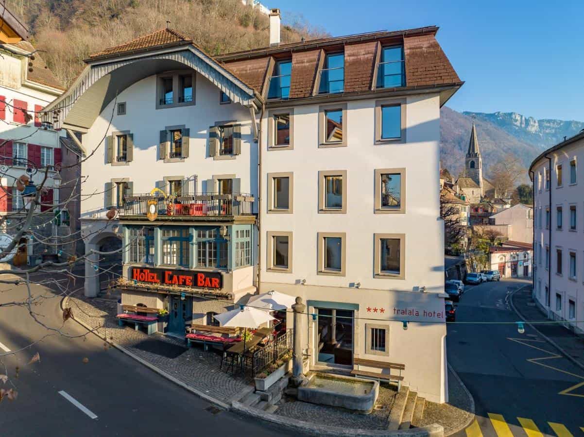 Hotel Cafe Bar Tralala in Montreux with mountain backdrop and church spire.
