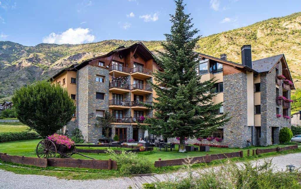 Stone and wood hotel building with balconies set against steep green mountains, Roca Blanca.