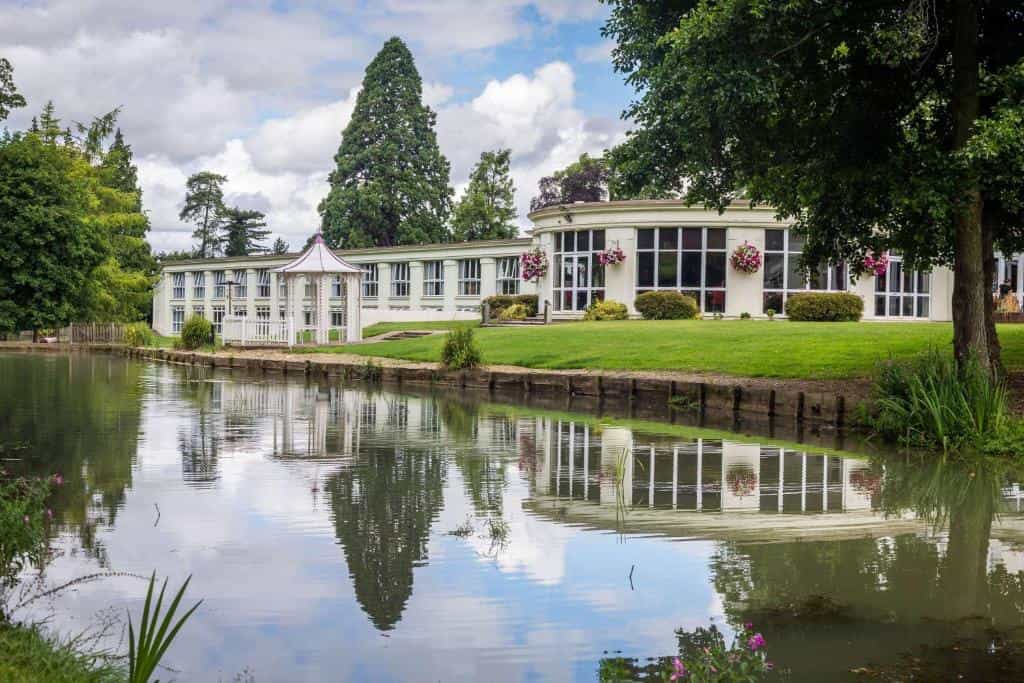 White building with large windows reflected in a calm pond with a white gazebo, DoubleTree-by-Hilton-Cheltenham.