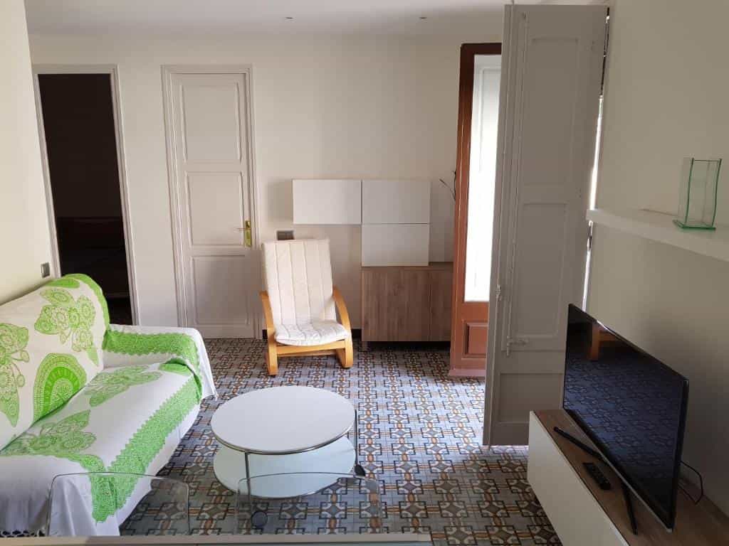 Living room with patterned tile floor, white and green sofa, and wooden armchair